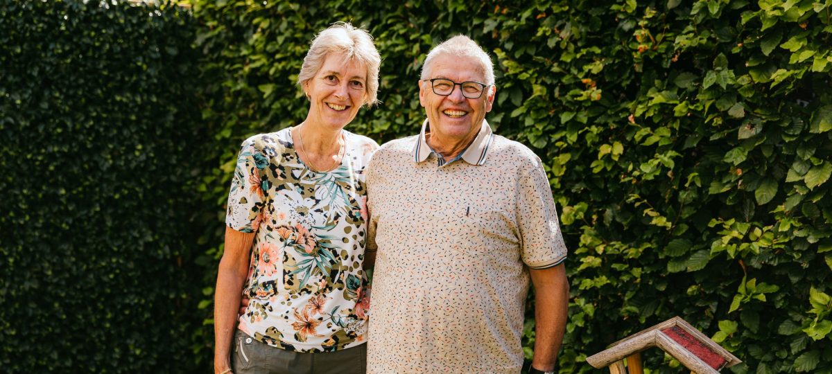 Het echtpaar Anja en Theo staan lachend in hun tuin op de foto