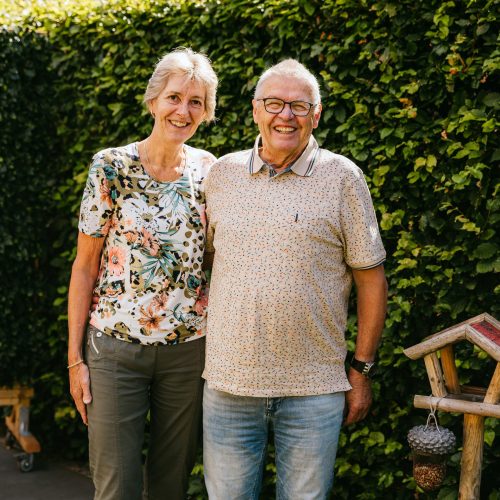 Het echtpaar Anja en Theo staan lachend in hun tuin op de foto
