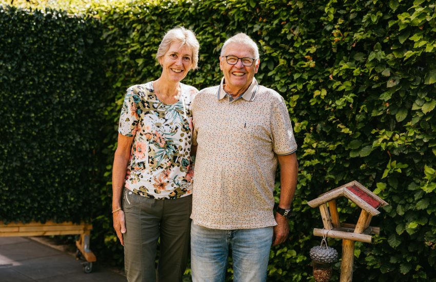 Het echtpaar Anja en Theo staan lachend in hun tuin op de foto