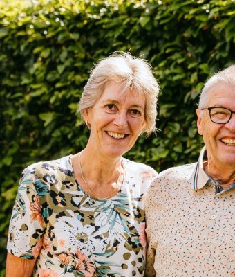 Het echtpaar Anja en Theo staan lachend in hun tuin op de foto