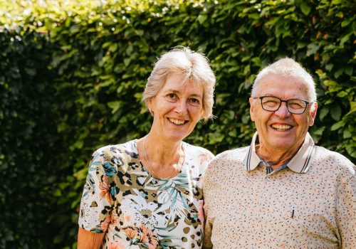 Het echtpaar Anja en Theo staan lachend in hun tuin op de foto