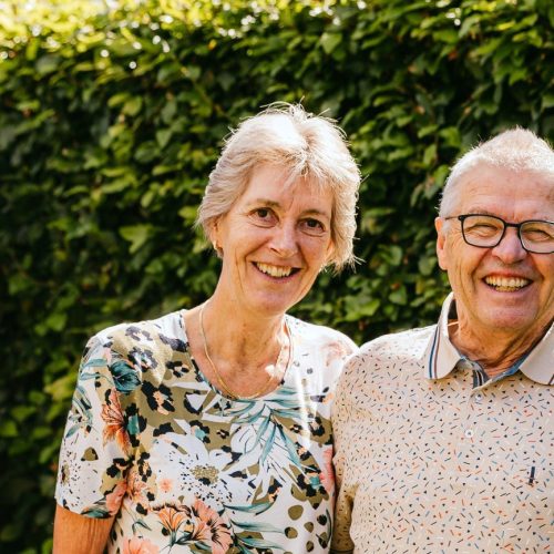 Het echtpaar Anja en Theo staan lachend in hun tuin op de foto