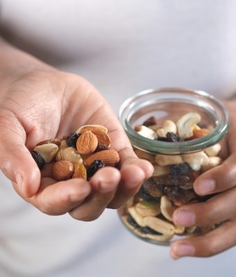 Bovenaanzicht van een handje noten uit een glazen pot