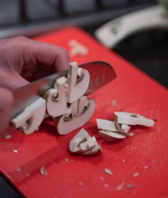 Champignons en paddestoelen snijden op een snijplank om een maaltijd voor te bereiden. Gezond eten