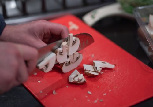 Champignons en paddestoelen snijden op een snijplank om een maaltijd voor te bereiden. Gezond eten