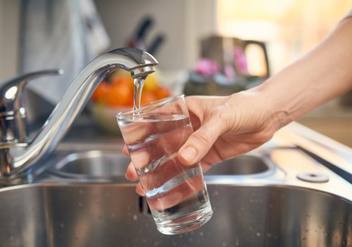 Een glas water vullen bij de kraan in de keuken