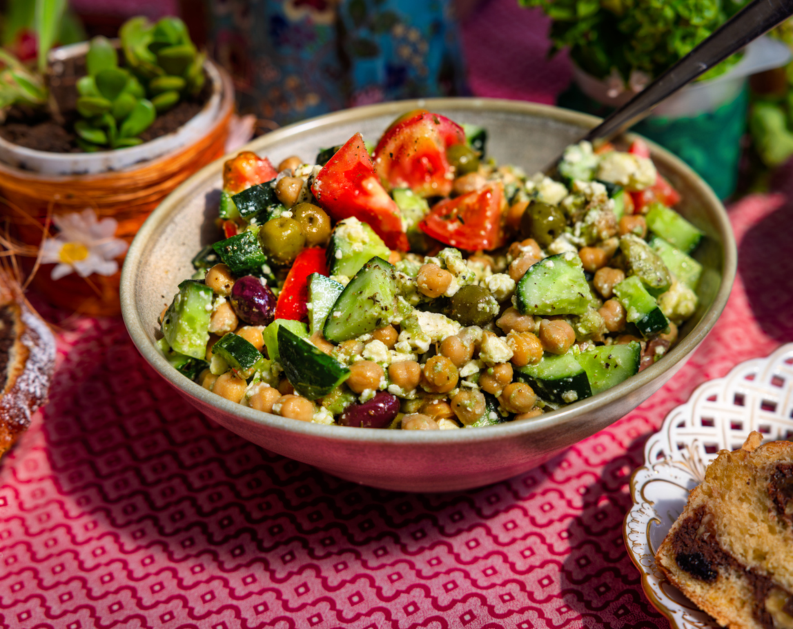 Gezonde kikkererwtensalade met komkommer, feta kaas, tomaat, olijven, kruiden in kom