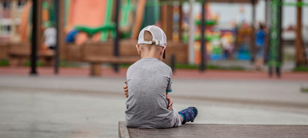 kind zit met zijn armen over elkaar, rug naar de camera